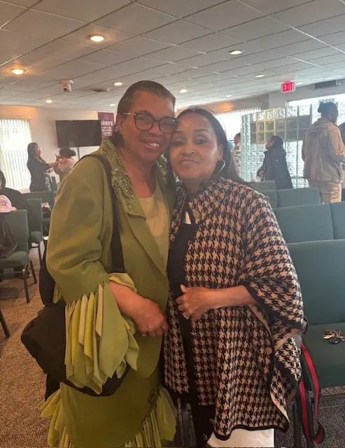 Two women smiling together at an indoor event.