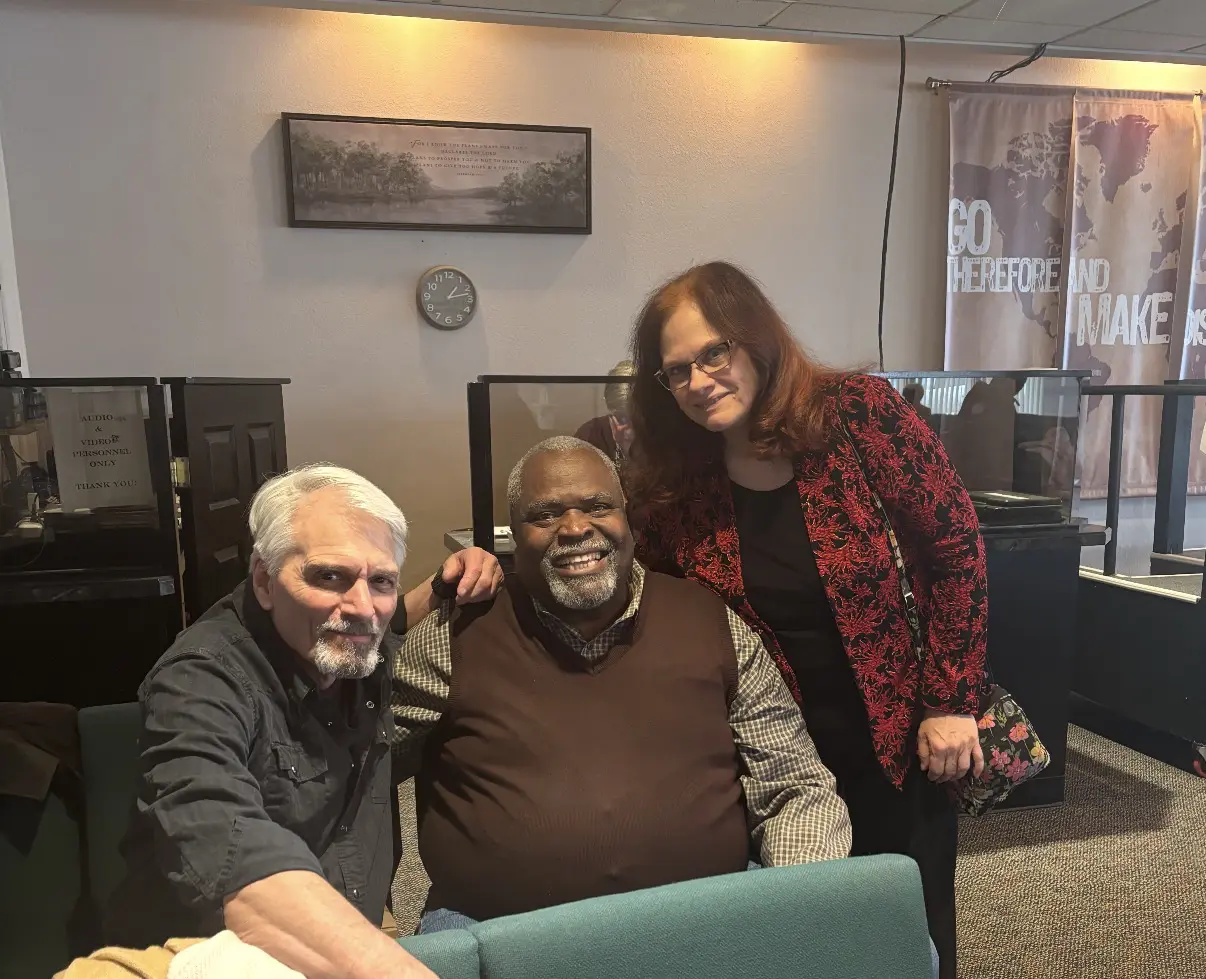 Three people smiling together in a cozy indoor setting.
