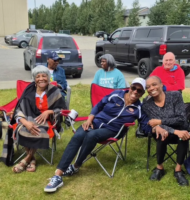 A group of people relaxing outdoors on lawn chairs.
