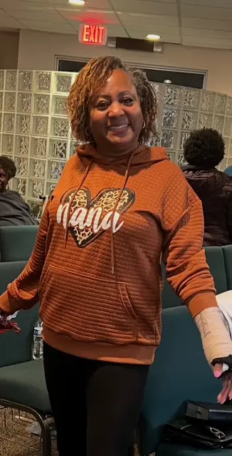 Woman smiling in an orange Hawaii hoodie.