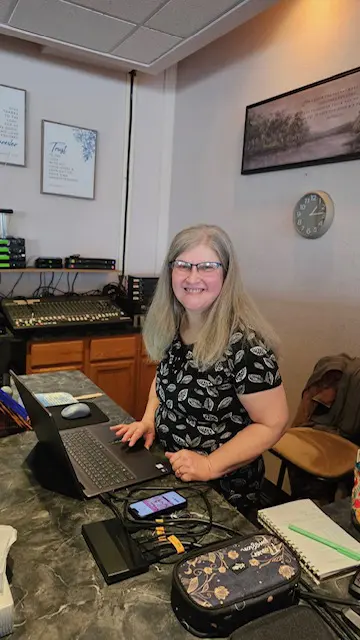 A smiling woman working on a laptop in a cozy room.