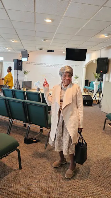 Elderly woman dressed elegantly in a church setting.